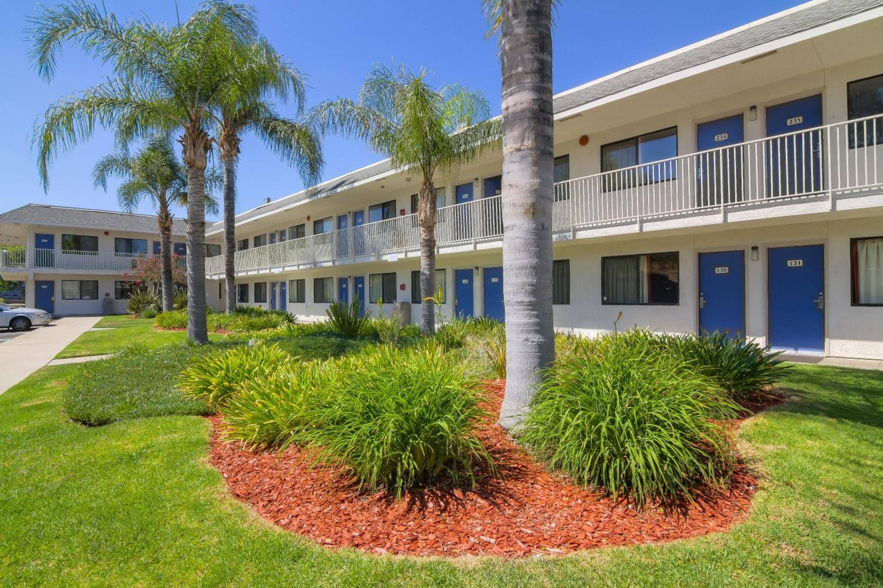 Un motel con varias habitaciones, cada una con una puerta azul y un balcón.