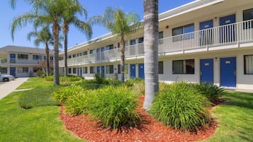 A motel with multiple rooms, each with a blue door and a balcony.