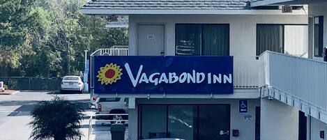 A two-story building with a sign reading "Vagabond Inn" and a parking lot with several cars.