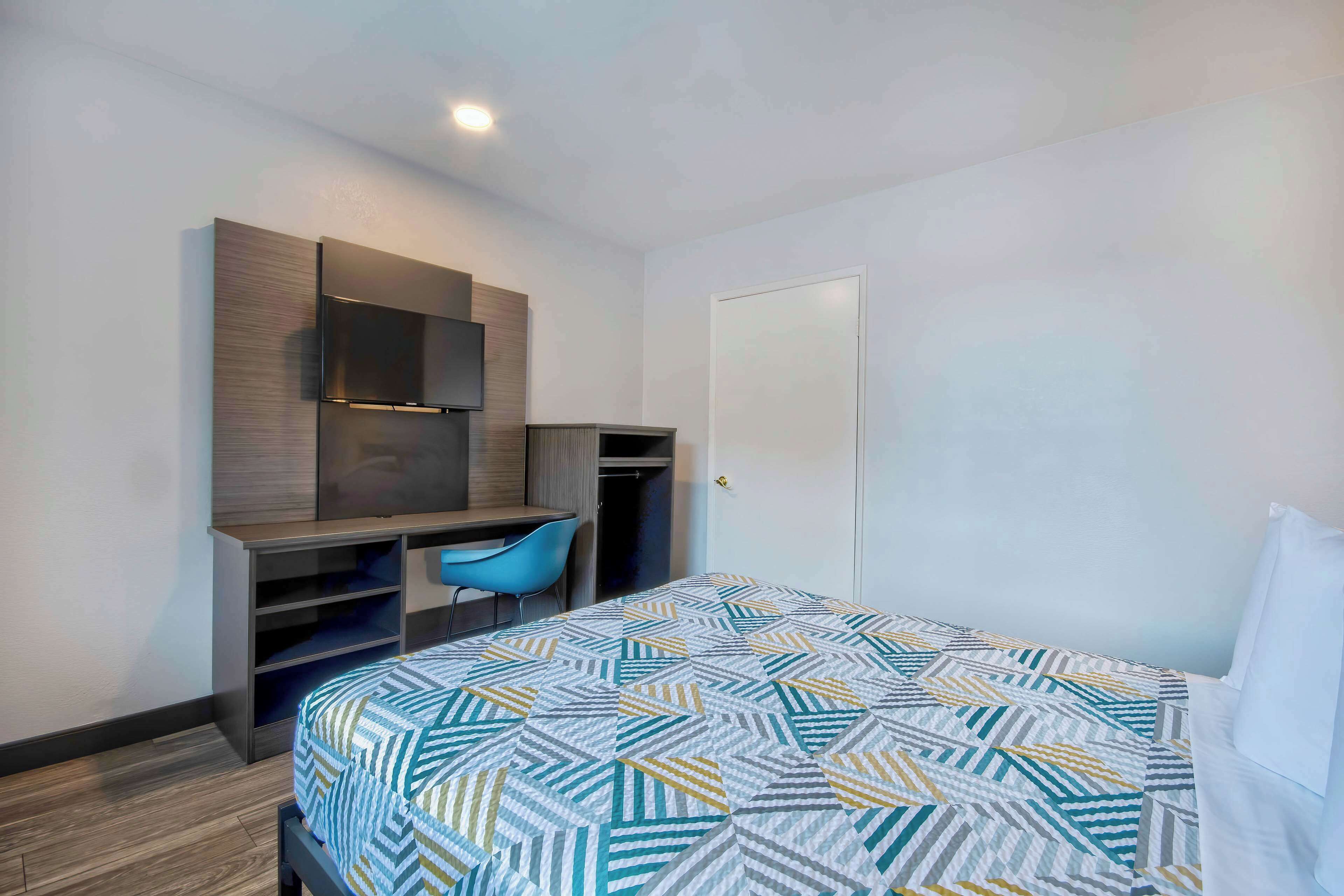 Una habitación de hotel con cama, escritorio, silla y armario.