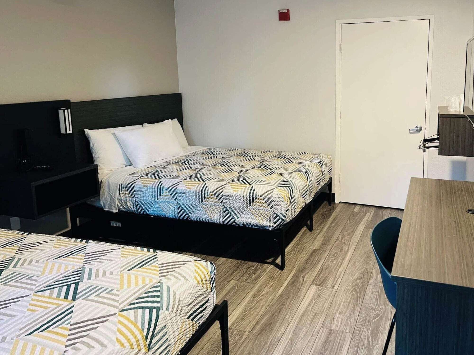 A hotel room with two single beds, a desk, and a chair.