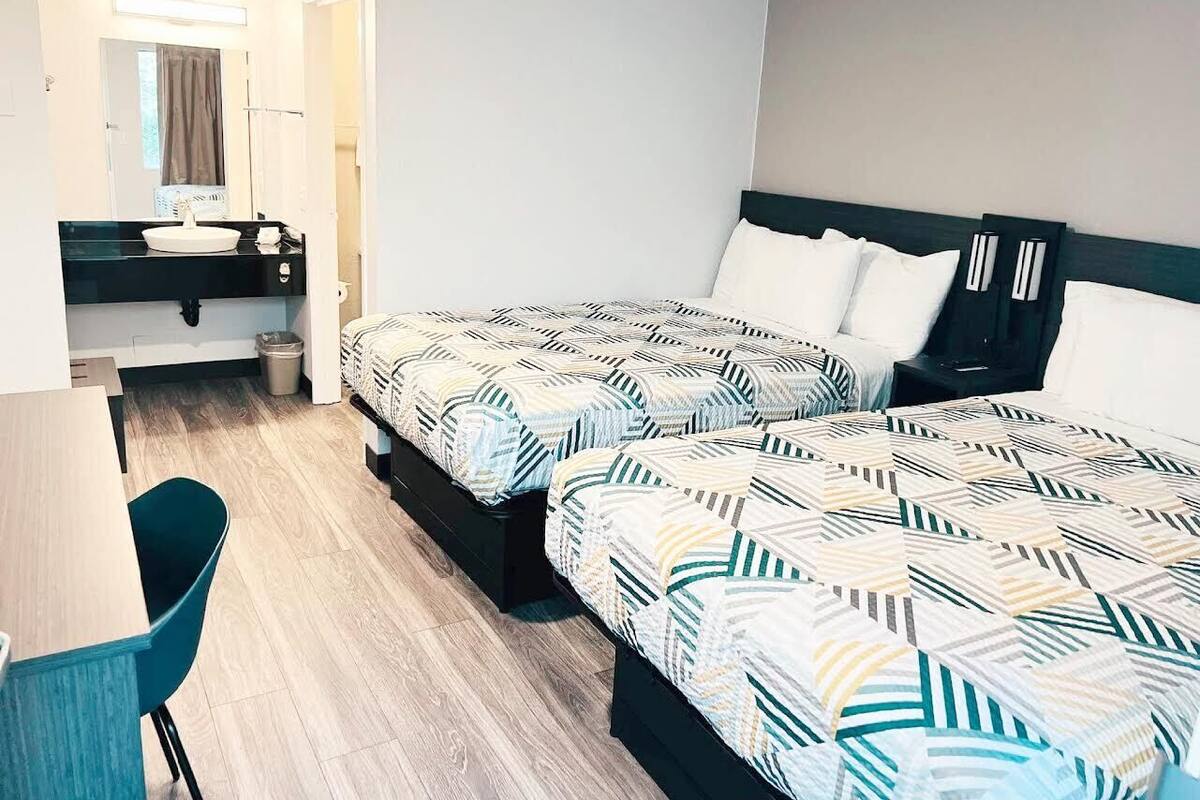 Ein Hotelzimmer mit zwei Betten, einem Schreibtisch und einem Stuhl.