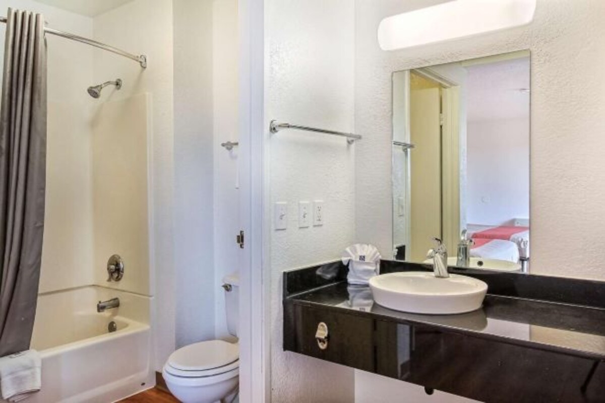 A bathroom with a bathtub, toilet, and a vanity with a sink and mirror.