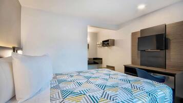 Una habitación de hotel moderna con una cama, un escritorio y un televisor montado en la pared.