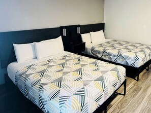 Twee enkele bedden met beddengoed met een geometrisch patroon, een donker hoofdbord en een nachtkastje met een lamp.