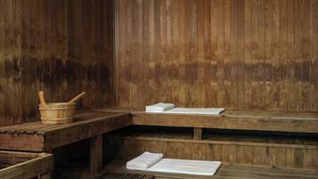 A wooden sauna with benches and a wooden table with towels and a wooden bowl.