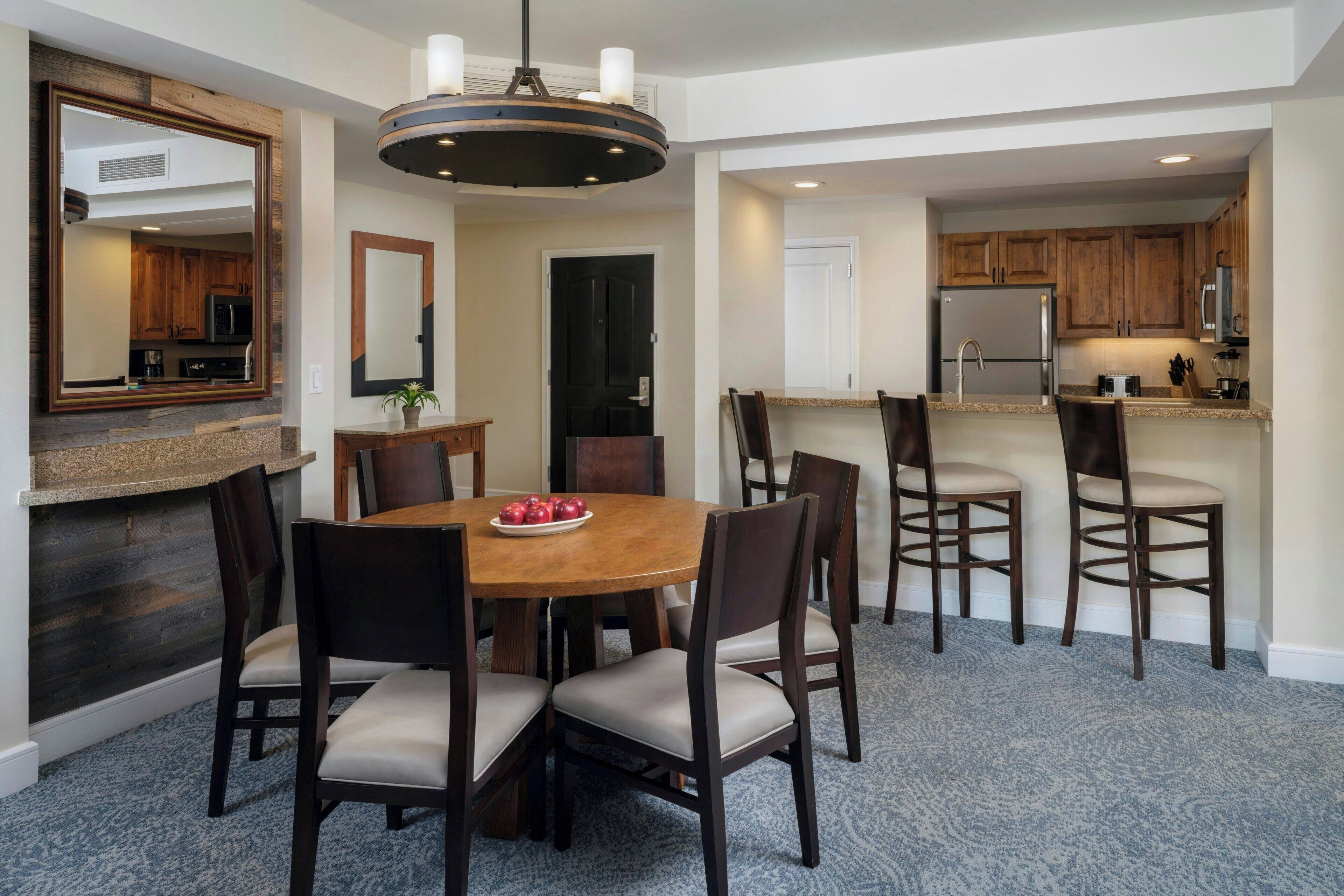A dining area with a round table, six chairs, and a chandelier.