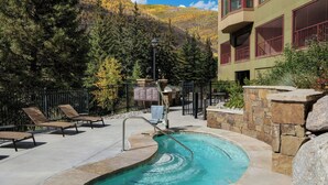 A swimming pool with lounge chairs, a stone wall, and a mountain backdrop. - Marriott's StreamSide Evergreen at Vail (Vail)