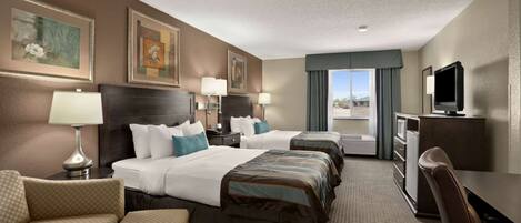 A hotel room with three beds, a desk, a TV, and a view of the outdoors.