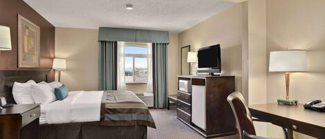 Una habitación de hotel con cama, escritorio, silla, televisor y cómoda.