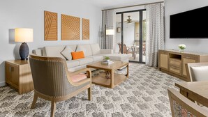 A modern hotel room with a sofa, armchair, coffee table, TV, and a dining area with chairs and a table. - Marriott's Sabal Palms (Orlando)