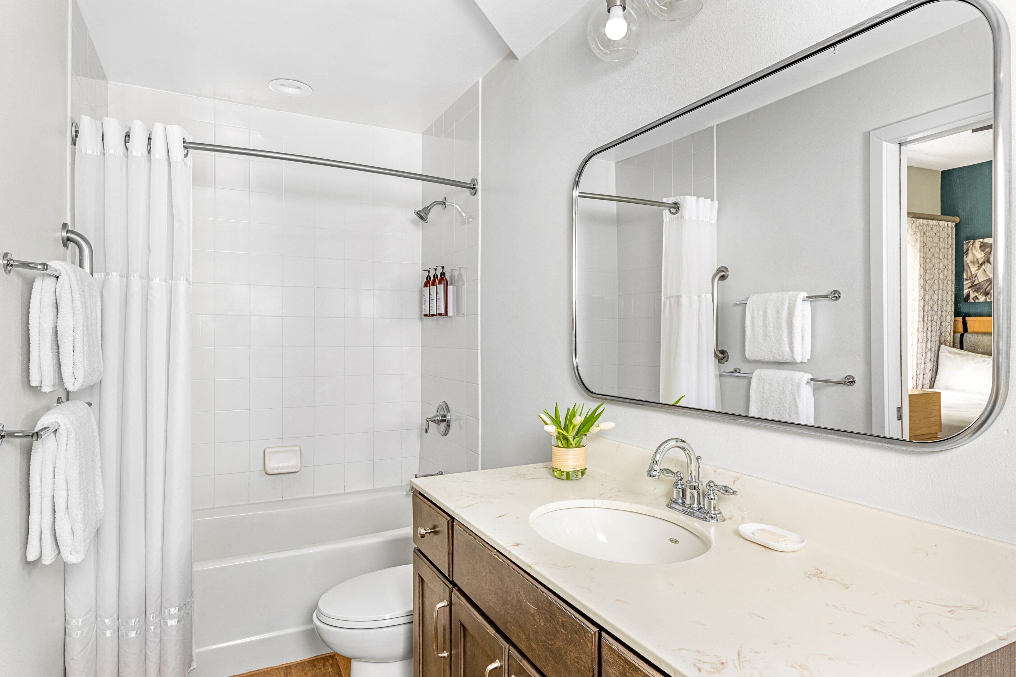 Een moderne badkamer met douche, toilet, wastafel en een grote spiegel.