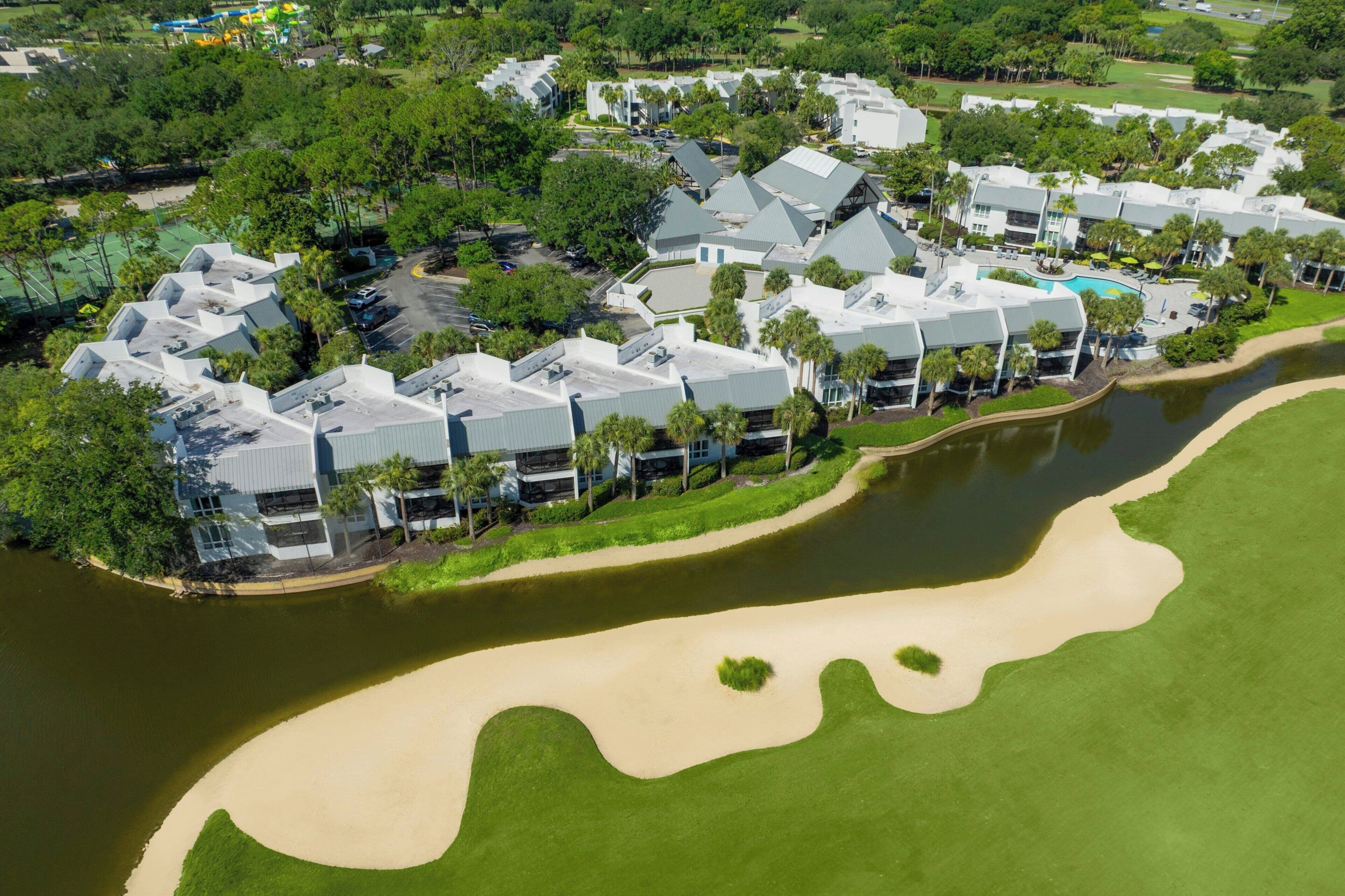 A resort with multiple buildings, a golf course, and a body of water.