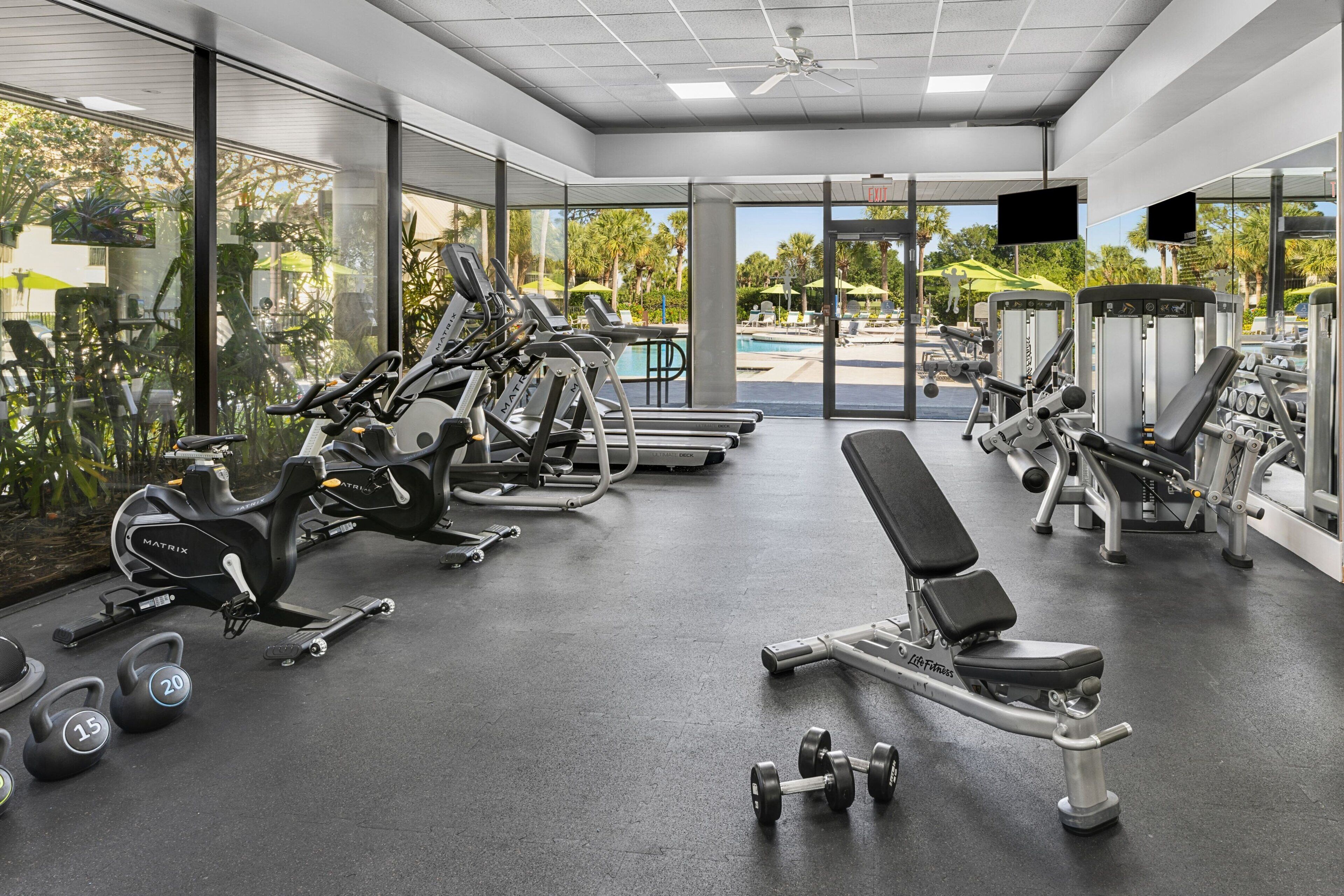 A modern gym with treadmills, weight machines, and dumbbells.