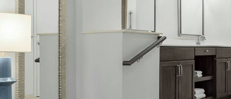 Un baño moderno con un espejo grande, un lavabo y una escalera que lleva a la zona de ducha.