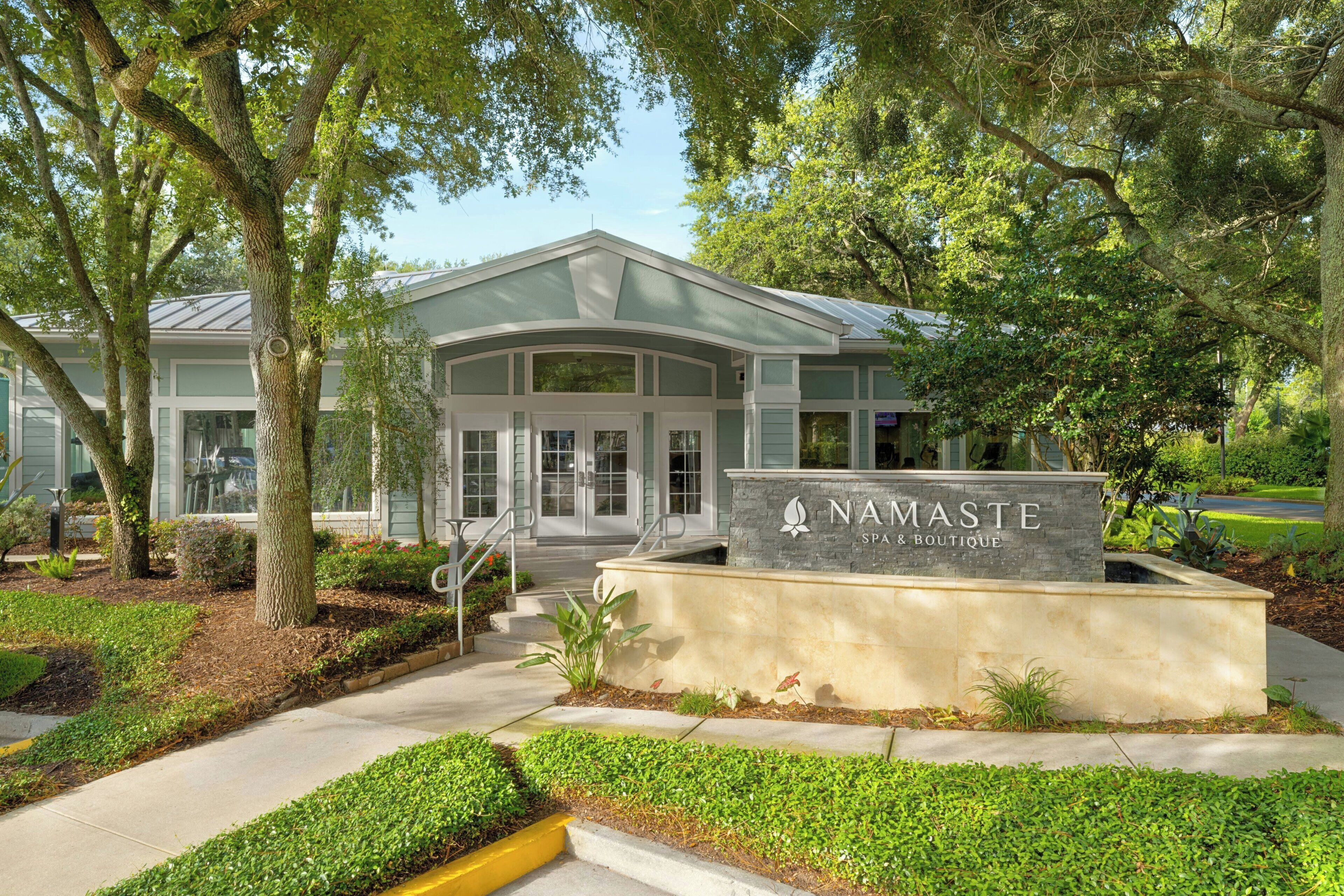 A spa and boutique building with a stone sign, a covered entrance, and a landscaped garden.
