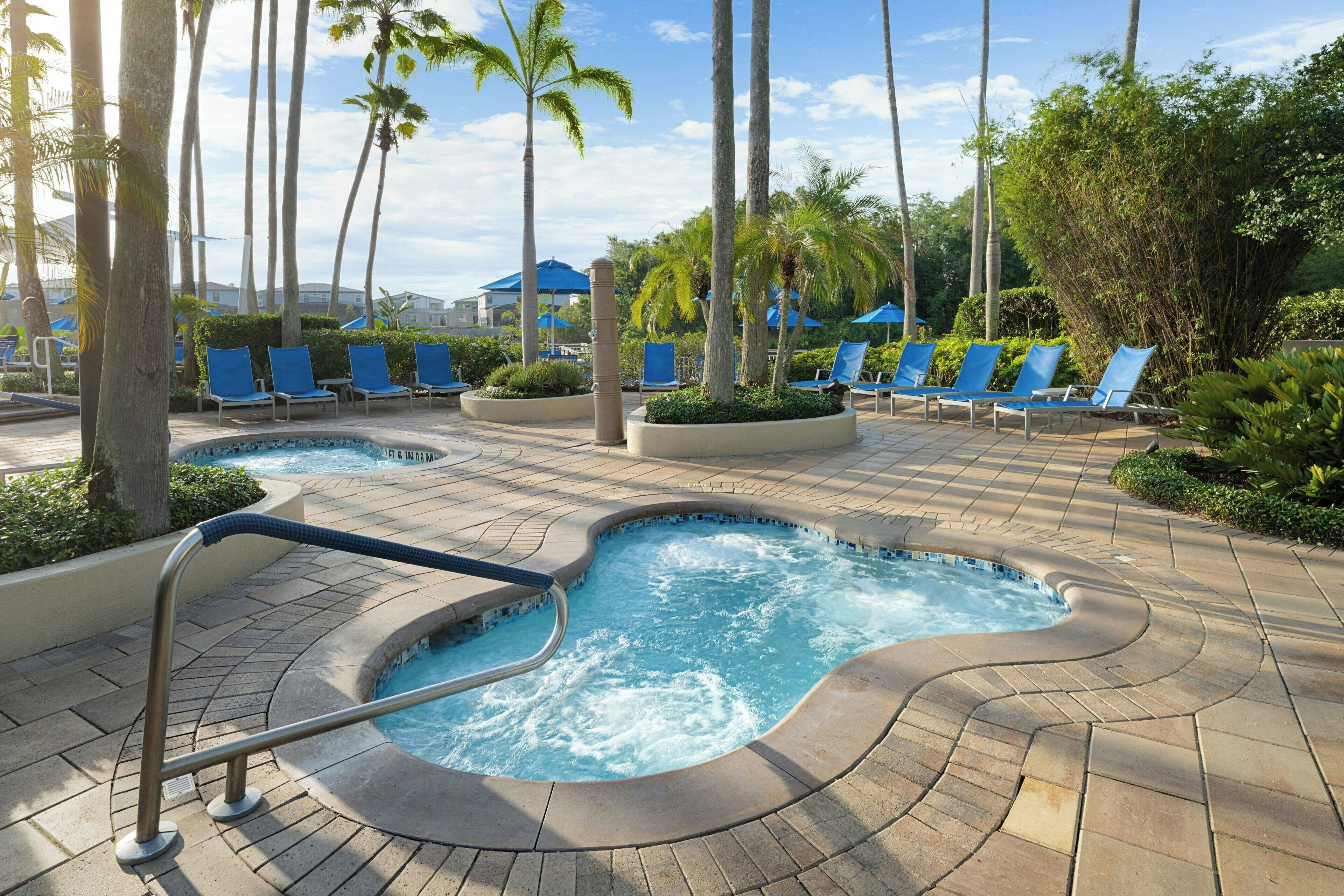 A pool area with lounge chairs and palm trees.