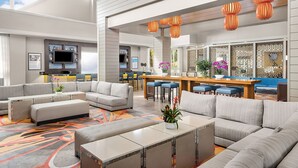 A spacious living area with a large sofa set, a coffee table, and a dining area with a kitchen in the background.