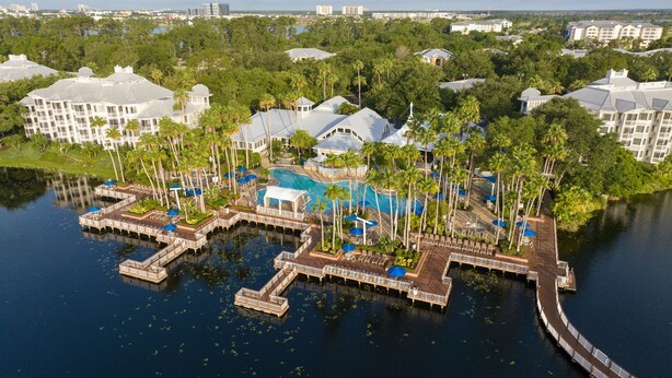 An aerial view of a resort with multiple buildings, a central pool, and docked boats.