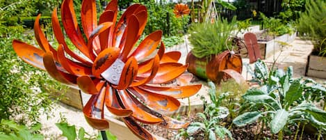 A garden with a large orange flower in the foreground and various plants in the background.