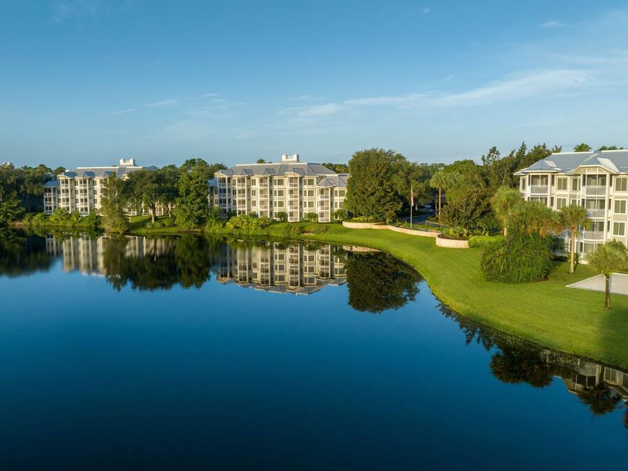 A waterfront hotel with multiple buildings, a calm lake, and a well-maintained lawn.