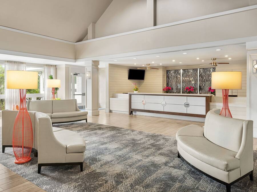 A spacious living room with a large gray rug, two beige sofas, and a modern entertainment unit with a flat-screen TV.