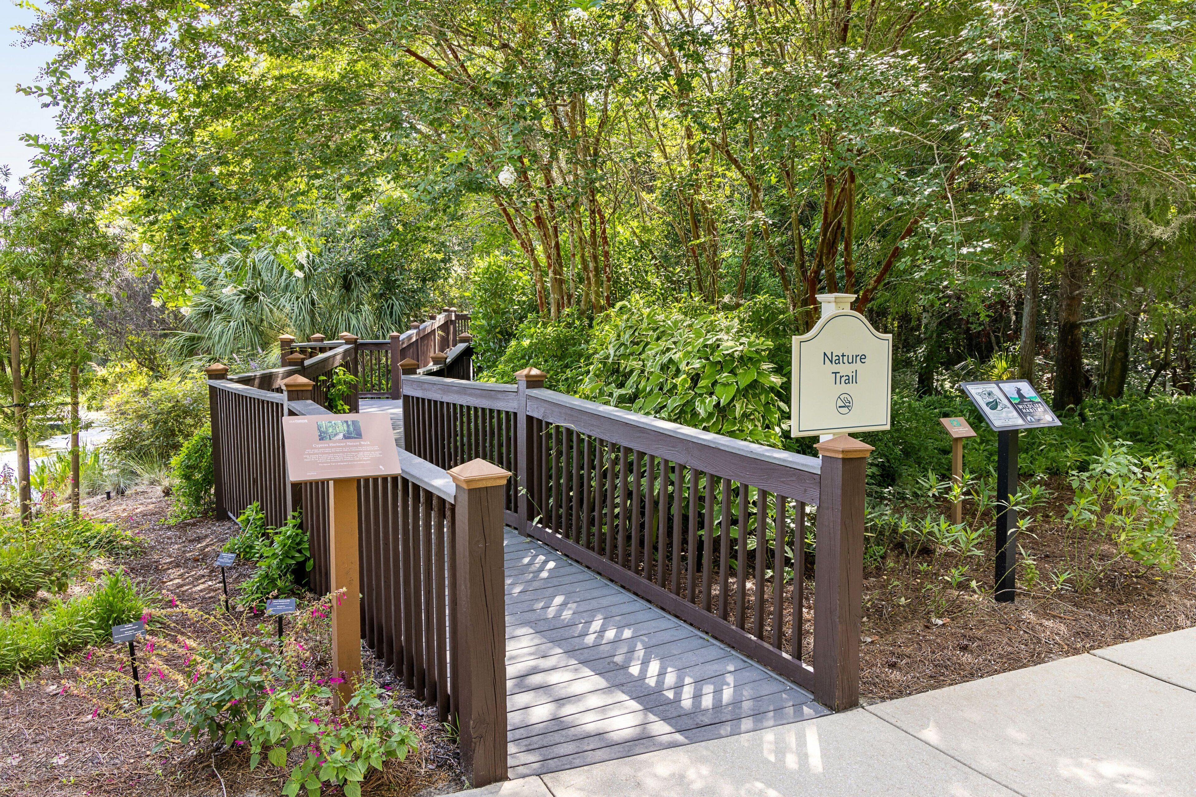 A wooden bridge leading to a nature trail with informational signs.