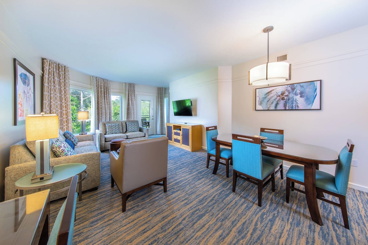 Una habitación de hotel con zona de estar, mesa de comedor y televisor.