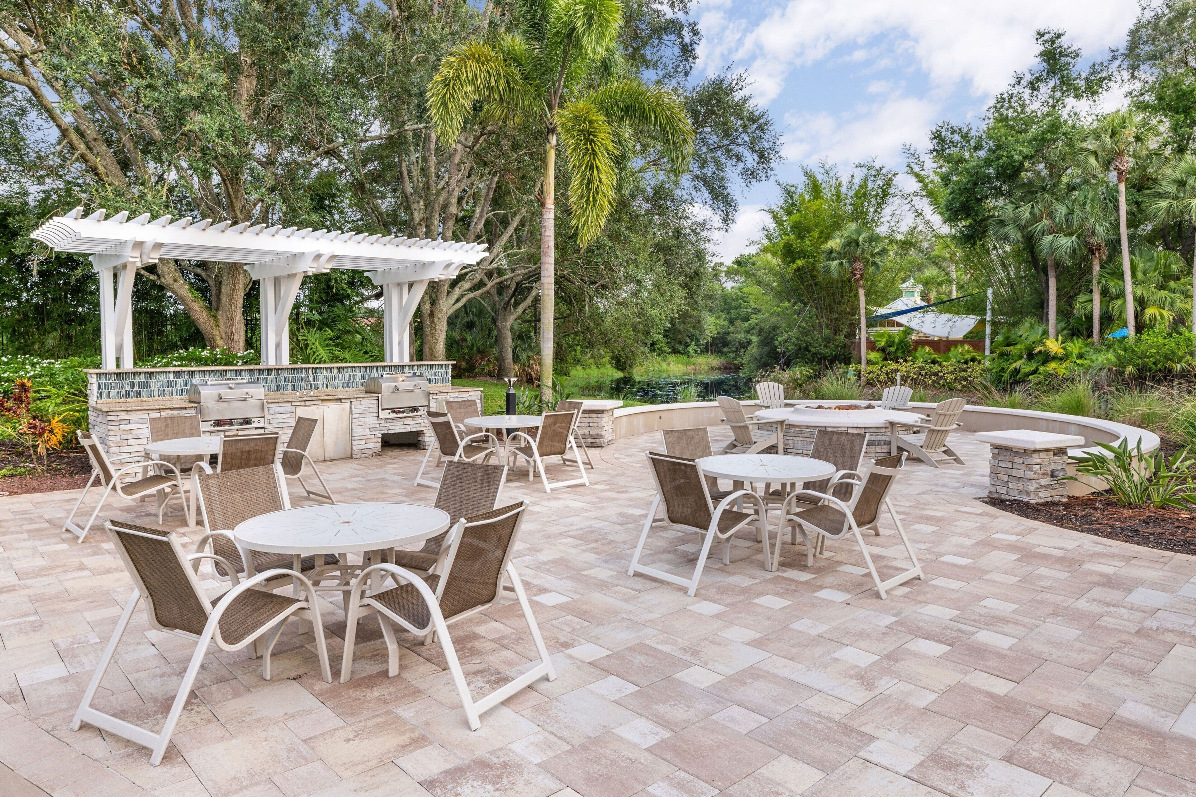 An outdoor patio with round tables and chairs, a pergola, and a stone fireplace.