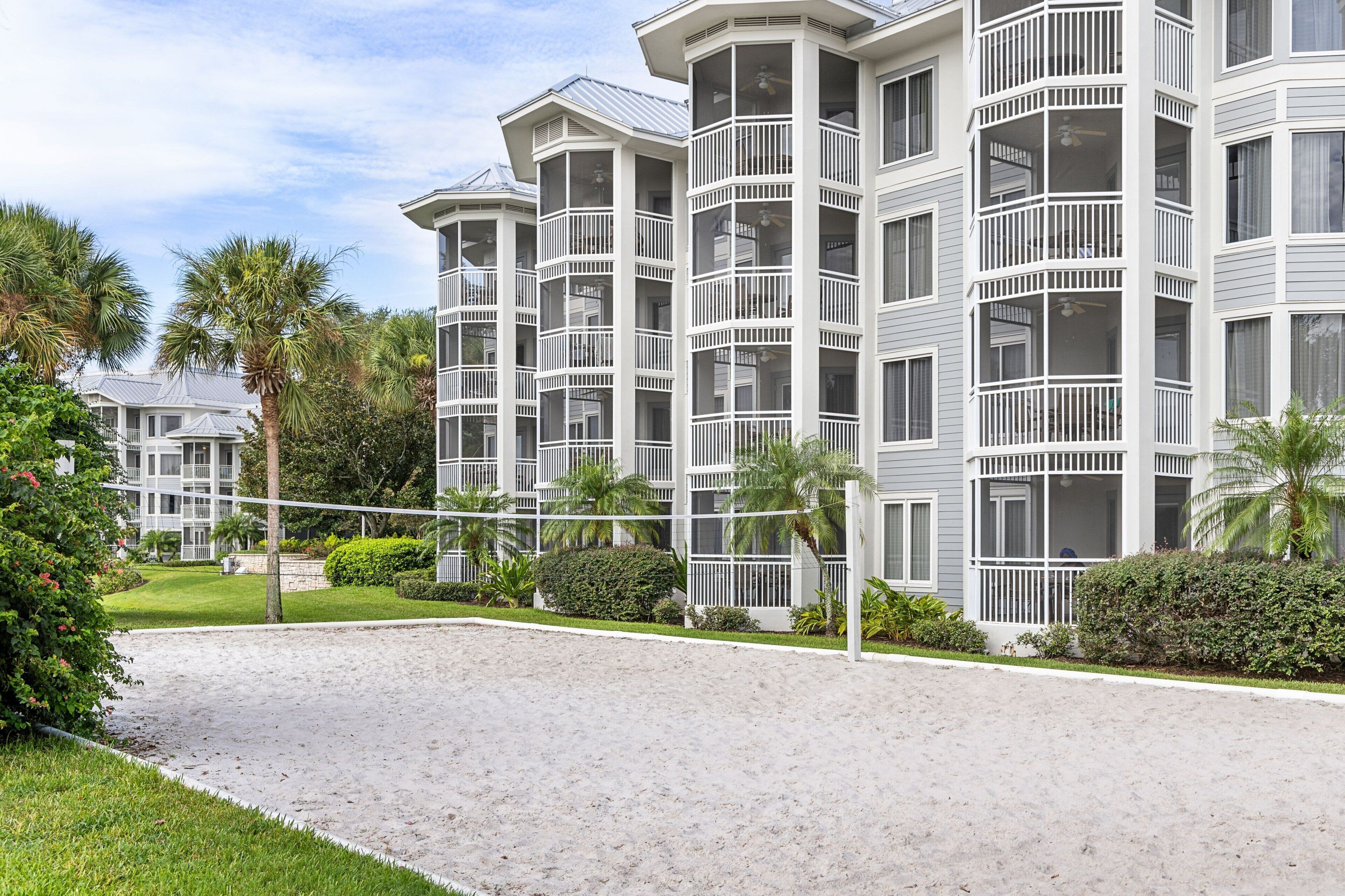 A multi-story hotel with balconies, a landscaped courtyard, and palm trees.