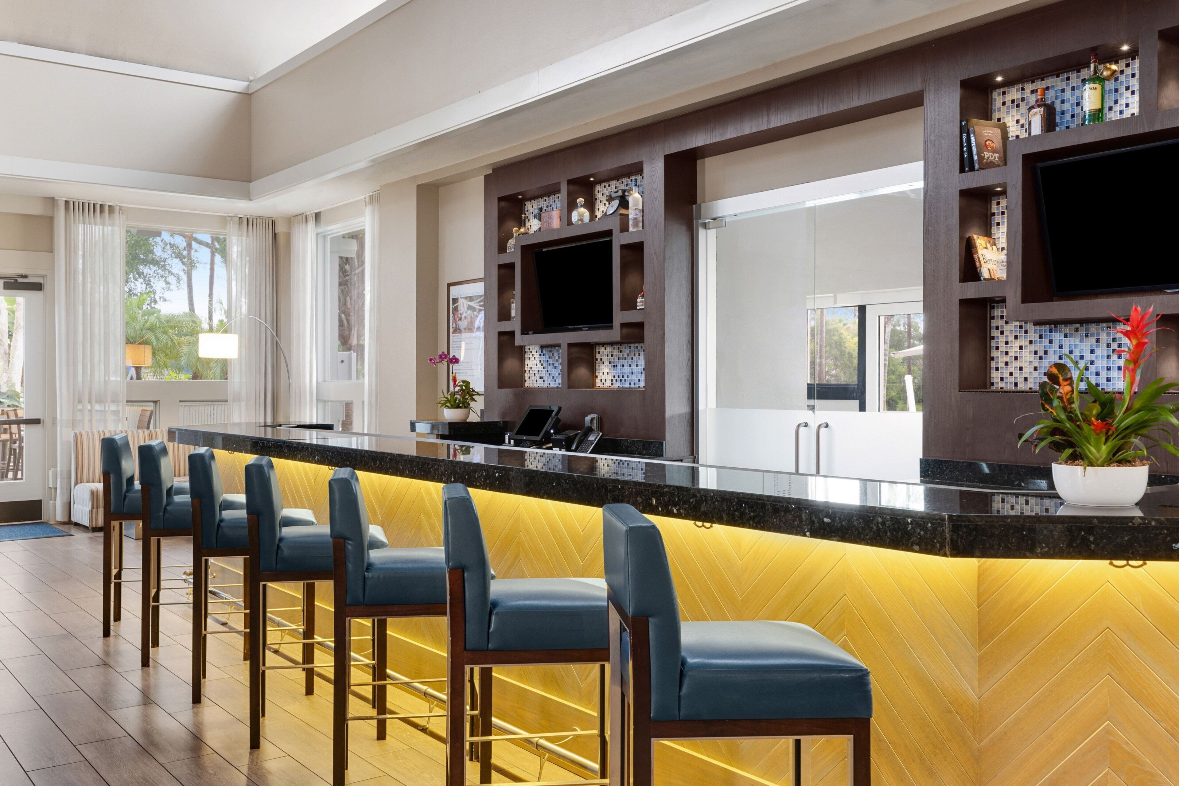 A modern kitchen with a bar area, built-in shelves, and a flat-screen TV.