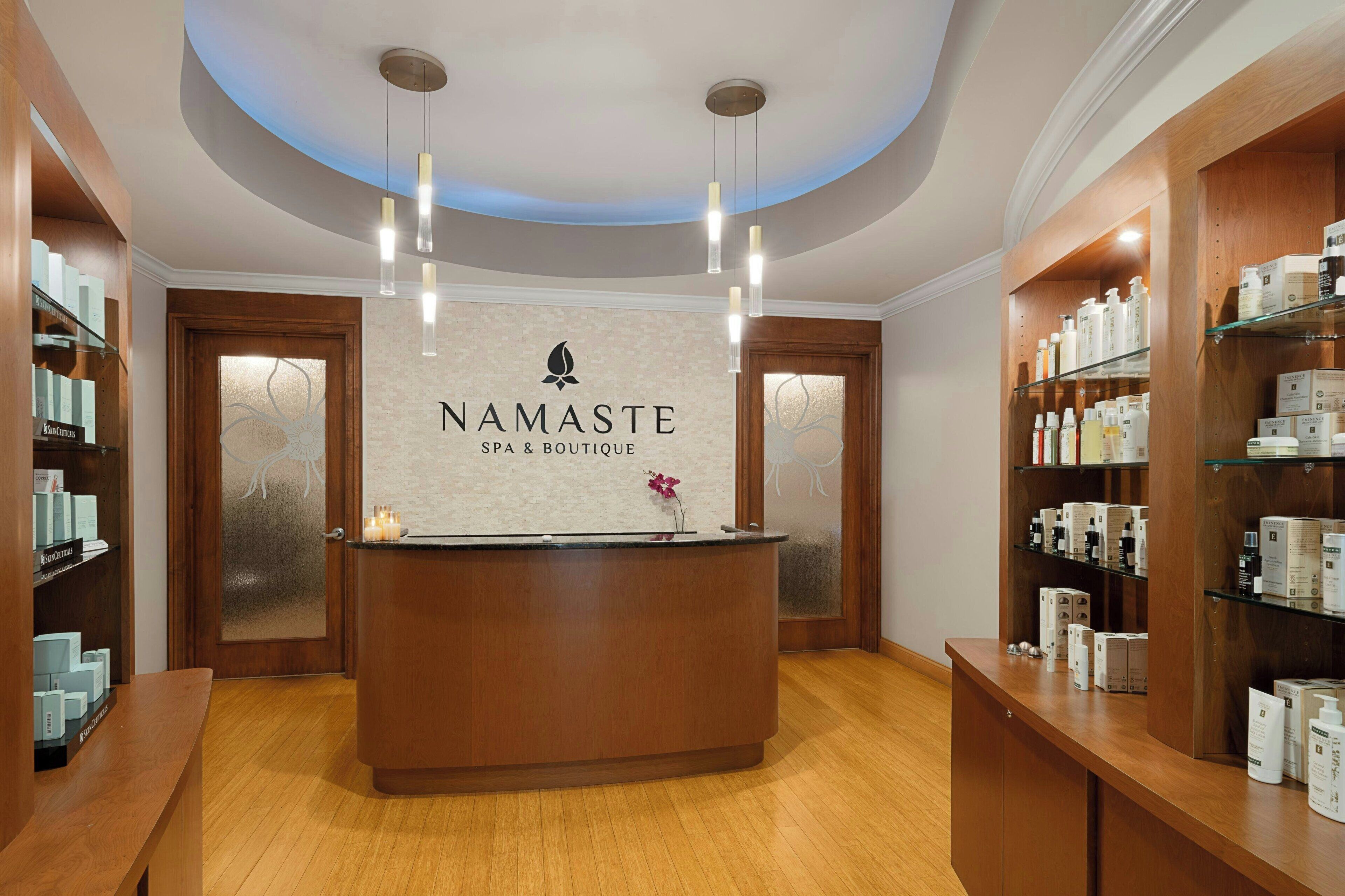 A reception area with a central desk, wooden shelving with products, and a ceiling with recessed lighting.