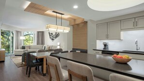 Una cocina moderna con una isla grande, electrodomésticos integrados y un comedor con una mesa larga y sillas.