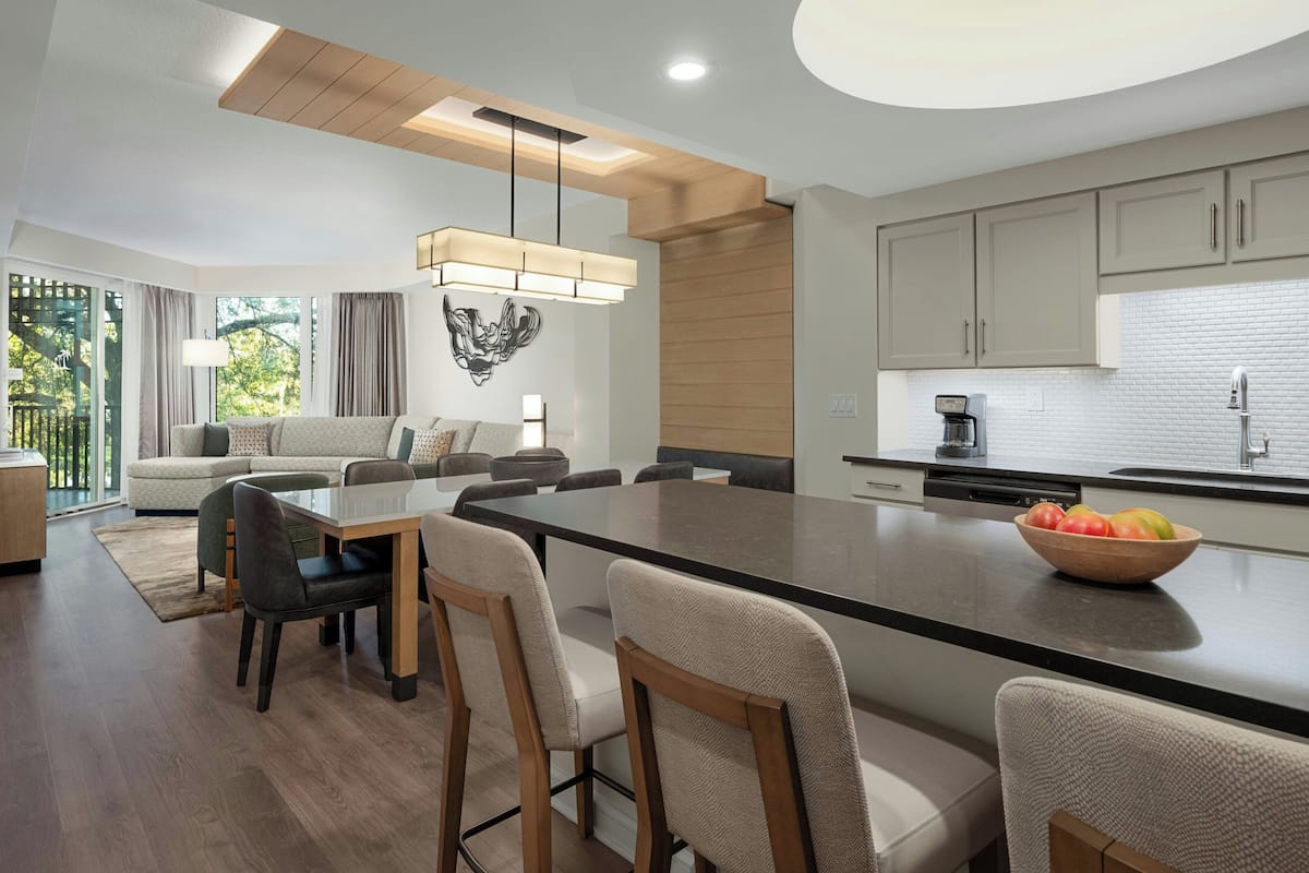 A modern kitchen with a large island, built-in appliances, and a dining area with a long table and chairs.