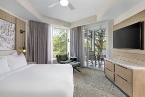 A hotel room with a large bed, a seating area with a chair, a TV, and a balcony with a table and chairs. - Marriott's Imperial Palm Villas (Orlando)