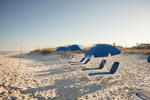 En la playa, arena blanca, sillas reclinables de playa, sombrillas