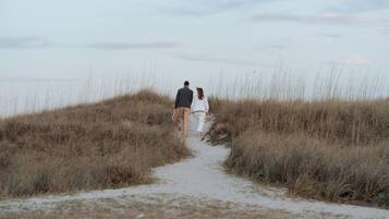 A pathway through tall grass leading to a body of water.