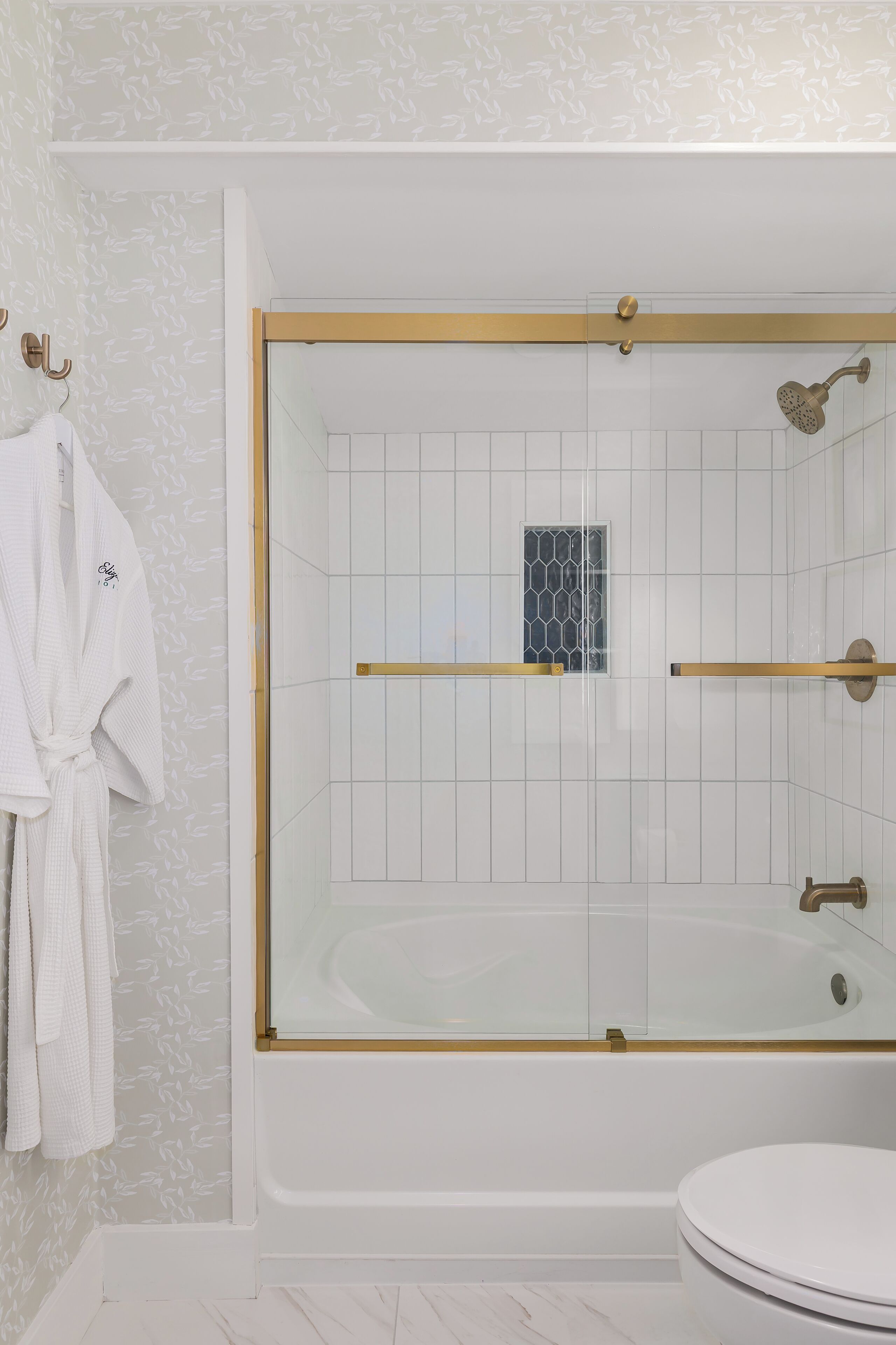 A bathroom with a glass-enclosed shower, a white bathtub, and a toilet.