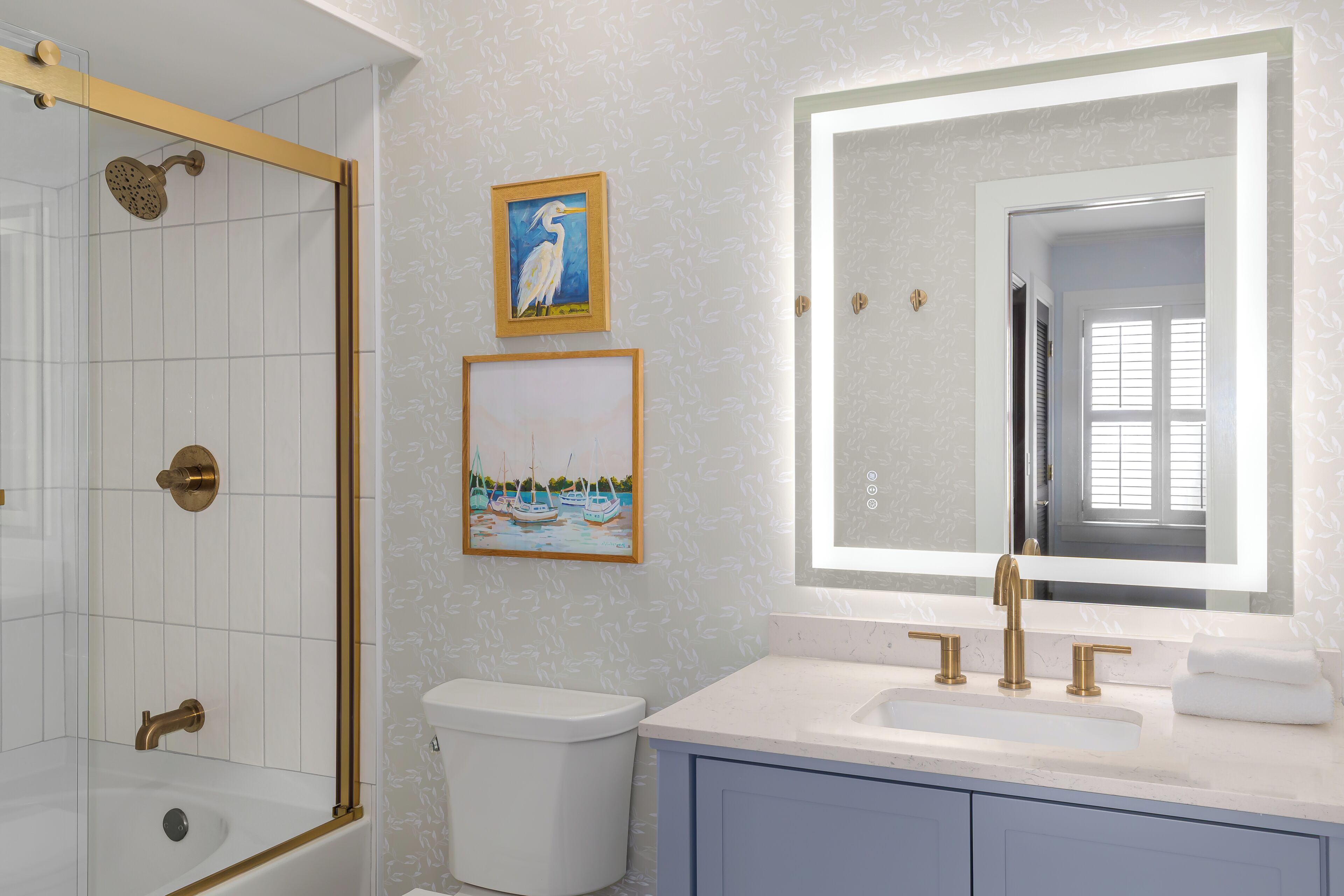 A bathroom with a bathtub, a toilet, a sink with a mirror, and two framed pictures on the wall.