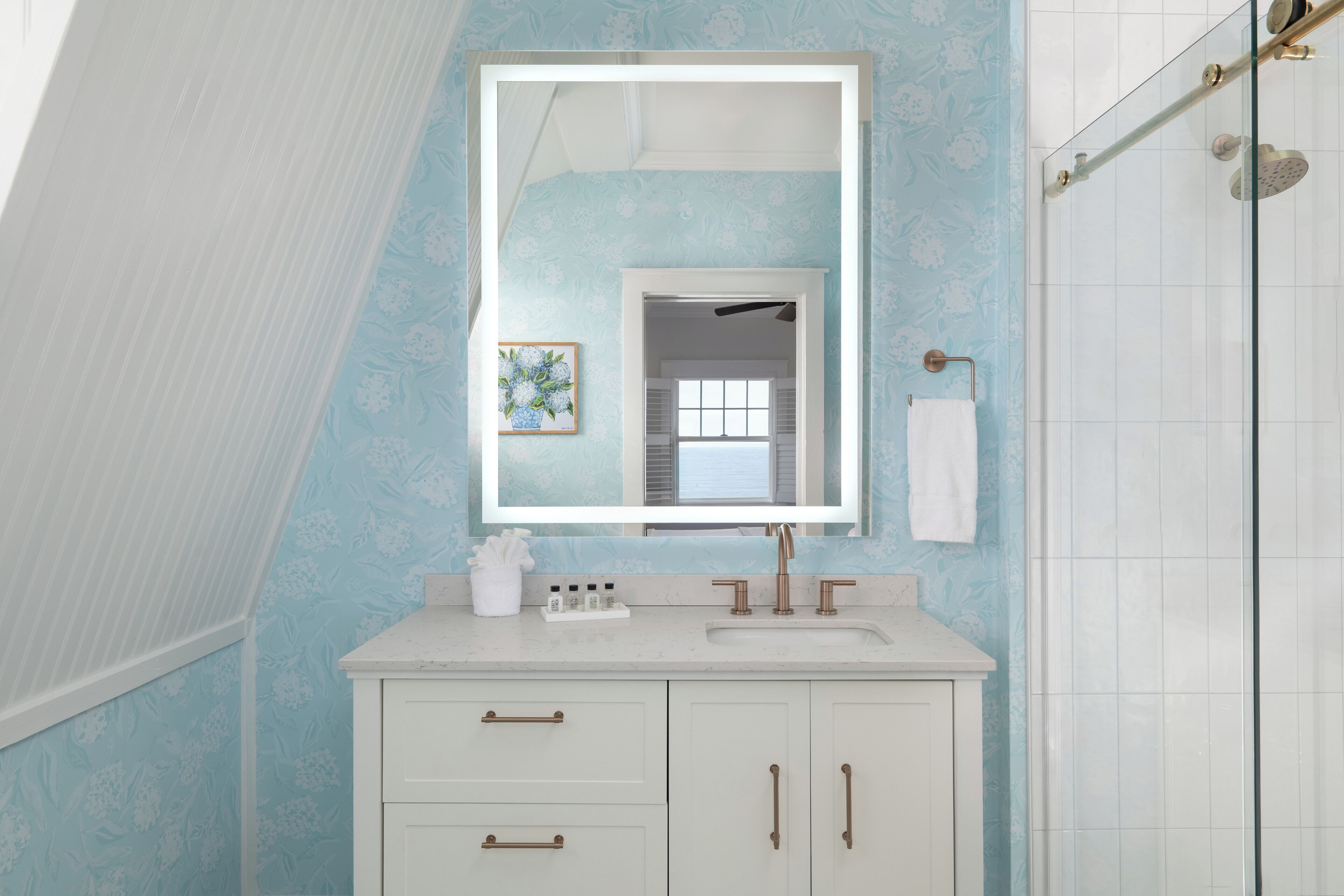 A bathroom with a white vanity, a large mirror, and a shower area.