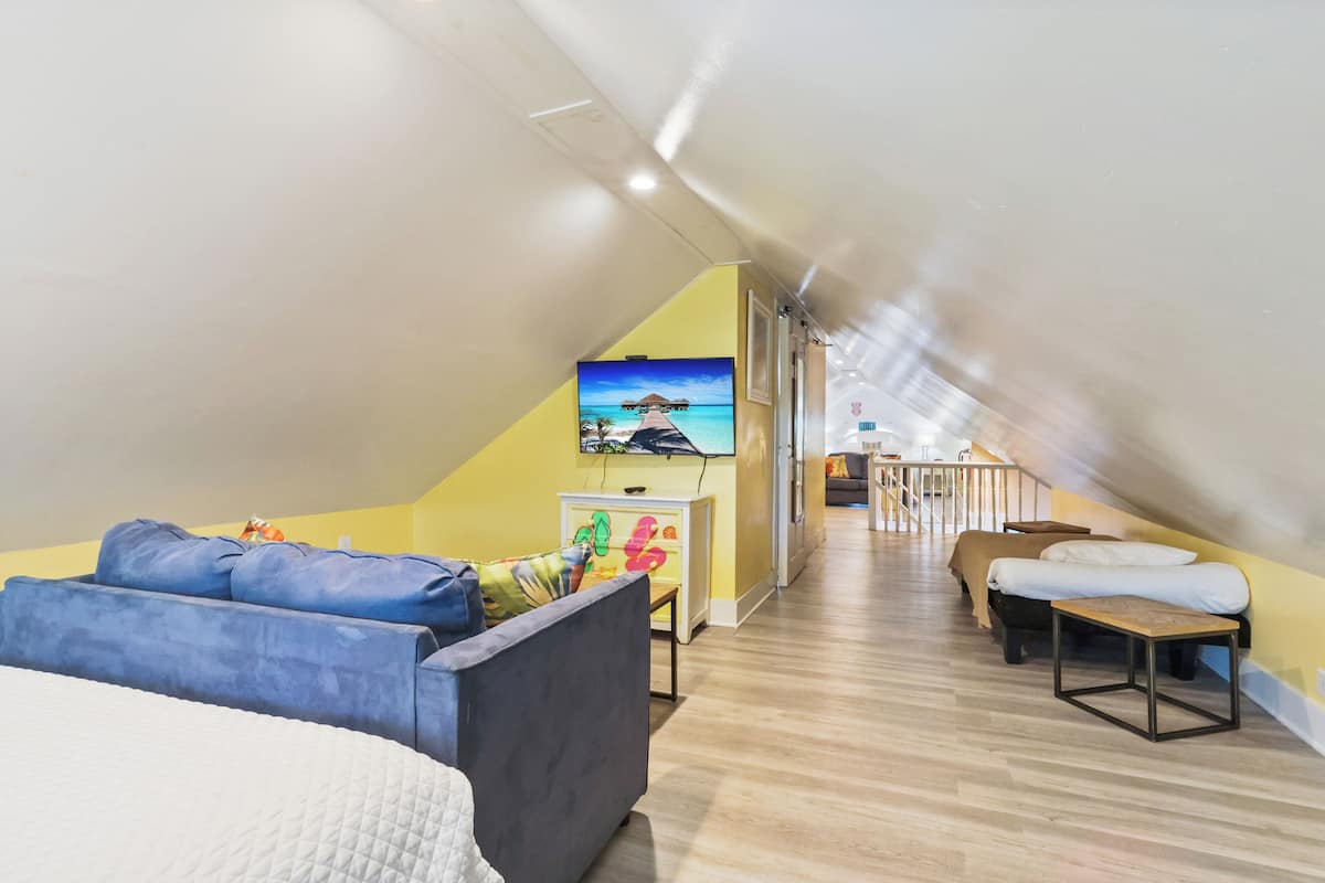 Une chambre spacieuse située dans les combles, comprenant un lit, un canapé, une télévision et une petite table.