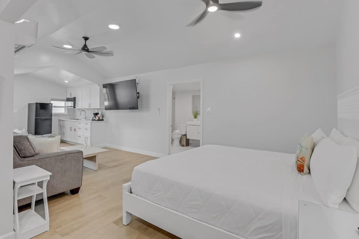Une chambre moderne avec un grand lit, un canapé, une télévision et un ventilateur de plafond.