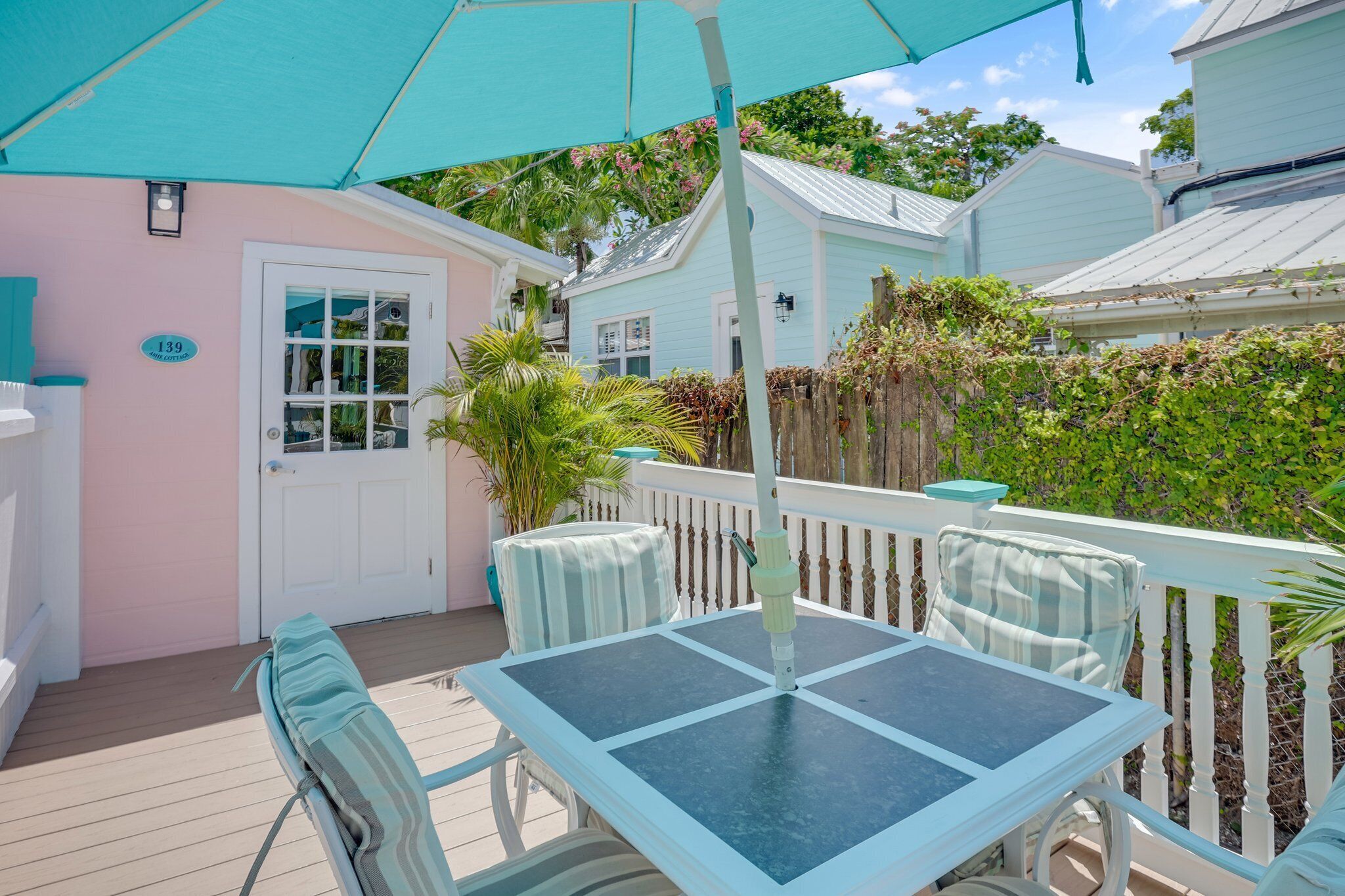 A covered patio with a table and chairs, a white door, and a sign with the number 139.