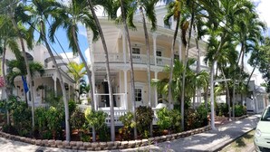 A hotel with a white facade, multiple balconies, and lush tropical landscaping.