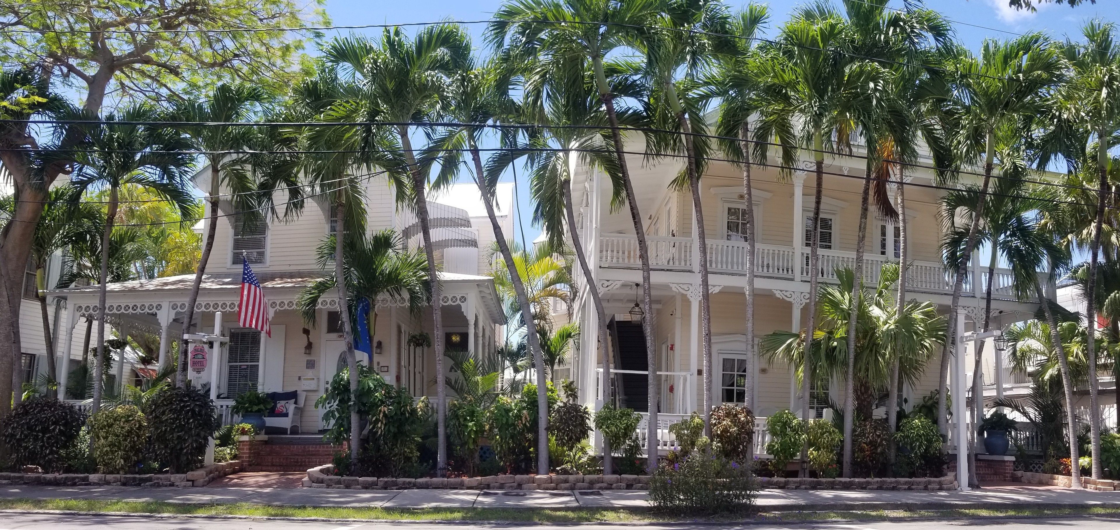 Un immeuble de deux étages avec une façade blanche, un balcon et un drapeau.