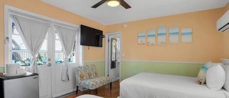 A hotel room with two beds, a ceiling fan, a TV, and a window with curtains.