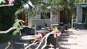 Un área de patio al aire libre con muebles de mimbre y plantas en macetas.
