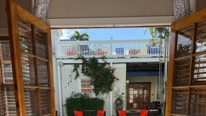 A hotel room with a large bed, a view of a swimming pool, and a balcony with outdoor seating.