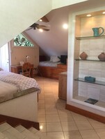 Une chambre à coucher comprenant un lit, un bureau, une chaise, un téléviseur et une étagère avec des objets décoratifs.