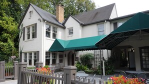 A two-story building with a covered patio area, outdoor seating, and a gated entrance. - The University Inn at Emory (Atlanta)